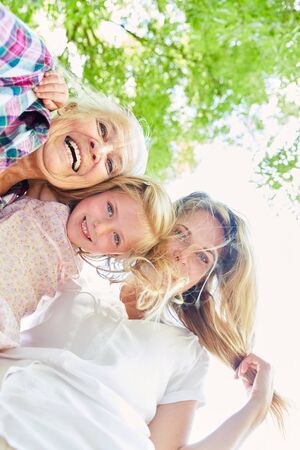 Happy girl as granddaughter with mother and grandmother in the sunshine