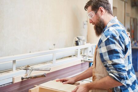 Carpenter with safety glasses when sanding wood on the grinding machine