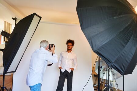Portrait photographer in the photo studio makes portrait photos of model in cool pose