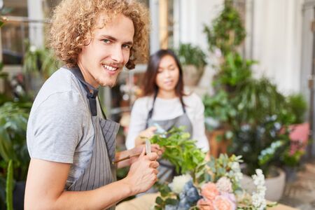 Young man as florist in training learns to tie bouquetの写真素材