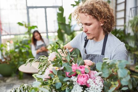 Young florist with flower scissors while cutting flowers in flower shop