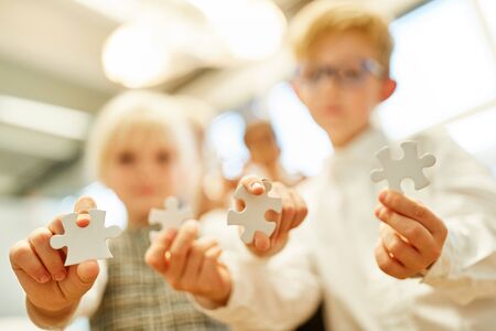 Children show different puzzle pieces as a sign of challenge and patience
