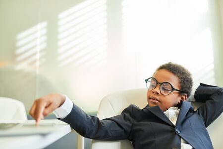 African boy disguised as a businessman or lawyer sits relaxed in the officeの写真素材