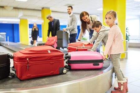 Passengers pick up their suitcases on the luggage rack after arriving at the airport terminalの写真素材