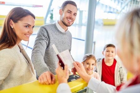 Family and children at the check-in counter in the airport terminal at the passport control
