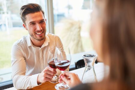 Young couple in love with toasting with a glass of wine in the restaurantの写真素材