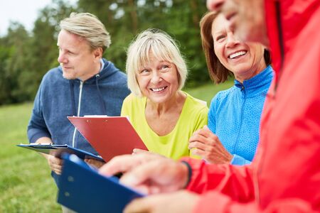 Group of seniors with clipboard during a scavenger hunt as a game on the groundの写真素材
