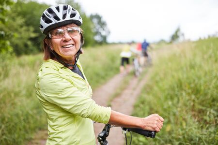 Vital senior woman on a bike tour together with friends in natureの写真素材
