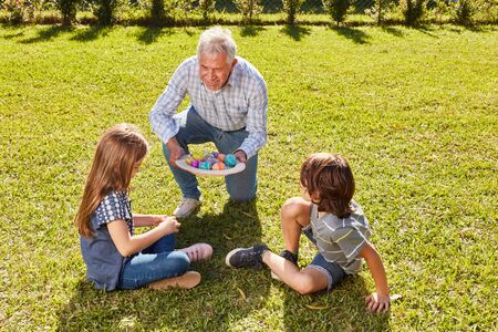 Grandfather and grandson at the easter eggs looking in the garden for easter in the sun