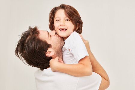 Happy single father kisses his son and lifts him upの写真素材