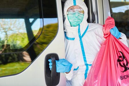 Transport and waste disposal of special waste from clinic by cleaning staff in protective clothing during coronavirus pandemicの写真素材