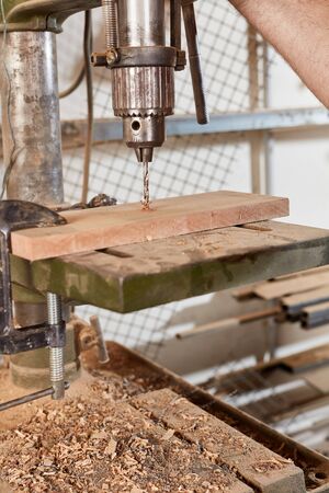 Drill drills a hole in a wood board in the carpentry workshop