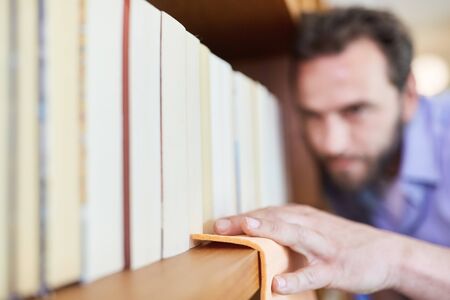 Housekeeper dusting on a bookshelf for cleanlinessの写真素材