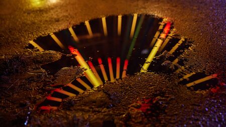 Illuminated ferris wheel is reflected at night in a puddle at the fun fair or a festivalの写真素材