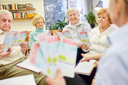 A doctor or therapist distributes a brochure on group therapy in a retirement homeの写真素材