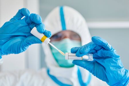 Medic in protective clothing with throat swab during saliva sample for coronavirus test