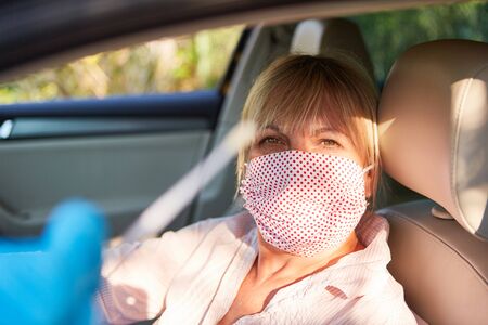 Elderly woman with face mask in her car drives in for quick test during the coronavirus pandemic