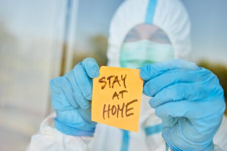 Stay at Home message on sticky note on door of clinic for coronavirus and Covid-19 pandemicの写真素材