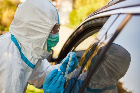 Corona virus test by containment scout from the health department with a throat swab in the drive-in...