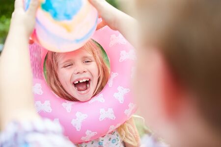 Laughing girl is kidding around with a swimming ring in the summer vacationの写真素材