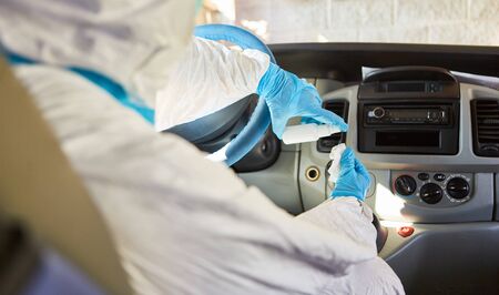 Cleaner in protective clothing cleans and disinfects ambulance interior due to coronavirus pandemicの写真素材