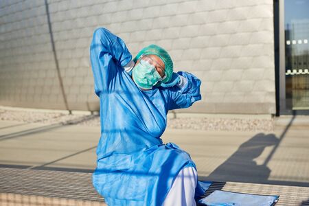 Doctor with tension and back pain in front of clinic due to stress and overload in coronavirus pandemicの写真素材