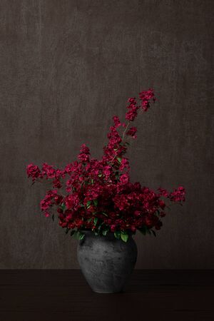 Red flowers as bouquet in flower pot on table next to dark wall (3D Rendering)の写真素材