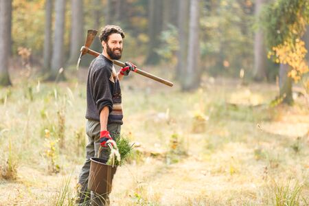 Young forest worker or forester with seedling while afforting for sustainabilityの写真素材