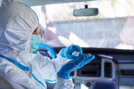 Cleaner in protective clothing applies disinfection to ambulance interior due to coronavirus...