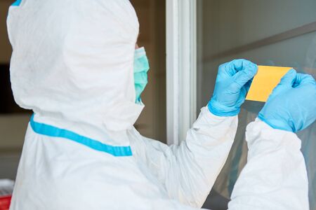 Employee attaches yellow sticky note to door or window of clinic during coronavirus epidemic