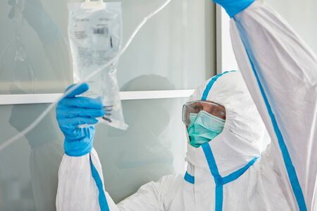 Doctor in protective clothing in intensive care unit prepares infusion for Covid-19 patient during...