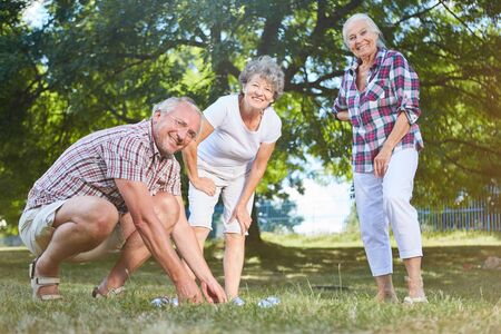 Seniors play boule or bocce together in the garden in summer in the retirement homeの写真素材