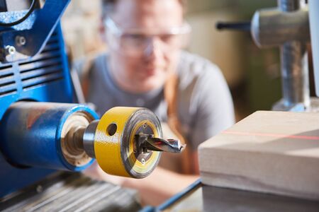Carpenter drilling wood with laser display in carpentry or joinery