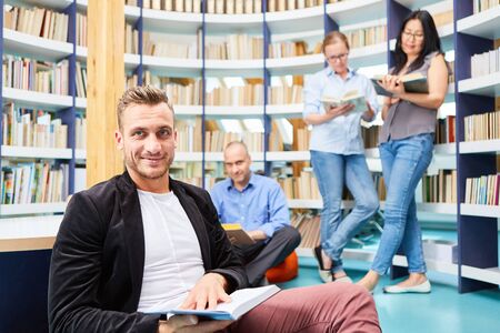 Man reading book together with young people in university library