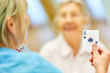 Nursing Woman plays cards with senior citizens in assisted living or at homeの写真素材