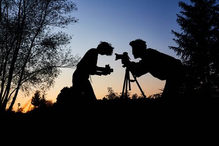 Young couple as hobby photographers take portrait photos at duskの写真素材