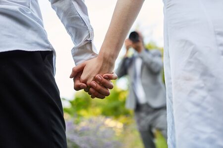 Wedding photographer takes pictures of hands of newlyweds on wedding day