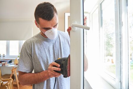 Man with respirator and grinder restore the window and grind