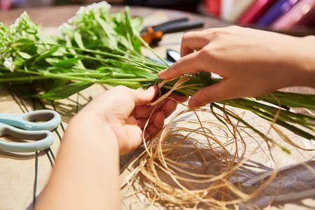 Hands of florist in flowers tying for a bouquet in the flower shopの写真素材