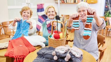 Seniors in the crochet course proudly display self-knitted socks and other clothingの写真素材