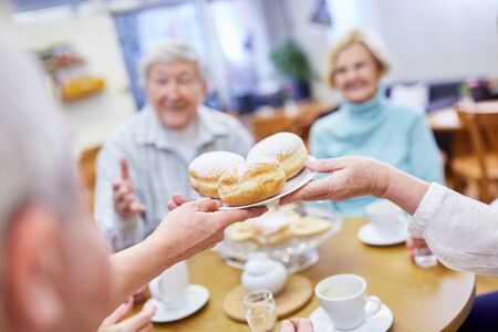 Seniors eat fresh Berlin pancakes in the common room in the retirement home