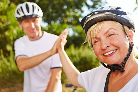 Woman and man with bike and helmet give each other high fiveの写真素材
