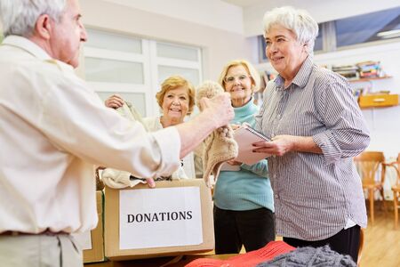 Seniors as volunteers collect clothing donation for the needy in the clothing storeの写真素材
