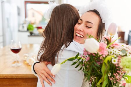 Girlfriend congratulates Brau with bridal veil at Hochzait with a hug and a bouquet of flowersの写真素材