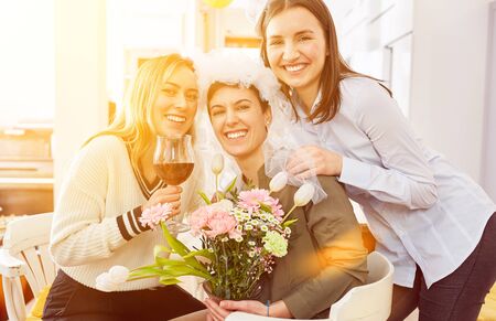 Laughing girlfriends celebrate with the bride at the wedding with flowers and wineの写真素材