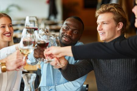African man is celebrating with his friends and toasting with a glass of wineの写真素材