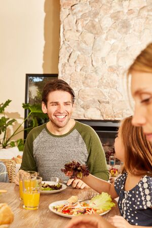 Father with daughter and wife at healthy lunch or dinner at homeの写真素材