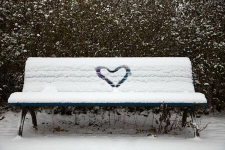 Heart painted in the snow on a snowy bench