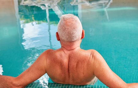 Senior man relaxes in swimming pool at Spa Wellness Hotelの写真素材