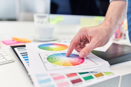 Hand of web designer points to the color palette in web development